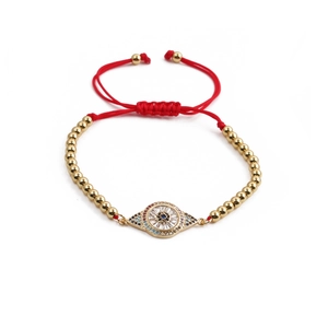 Détail d'un bracelet tressé rouge avec perles dorées et pendentif œil de protection