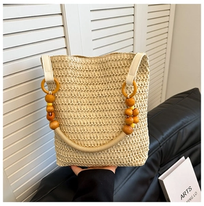 Detailed view of handmade woven straw tote bag with decorative wooden beads and rope handle