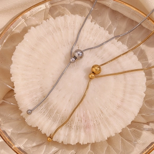 Detail of gold and silver Y-shaped snake chains with adjustable beads on coral tray