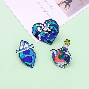 Three-piece ocean enamel pin set with whale in bottle and glacier wave designs