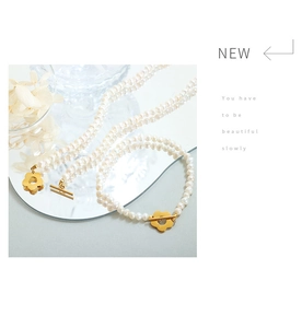 Detailed view of freshwater pearl necklace set with gold flower-shaped OT clasp closure