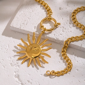 Detail of vintage gold sun face pendant with thick cuban chain on a stone block