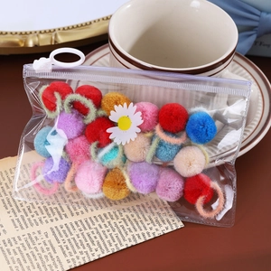 Élastiques à cheveux boules en peluche colorées dans un sac sur un livre ouvert