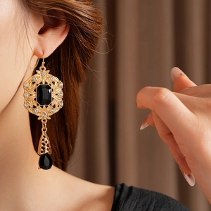 Detailed close-up of vintage gold hollow-carved earrings with black stones and rhinestones