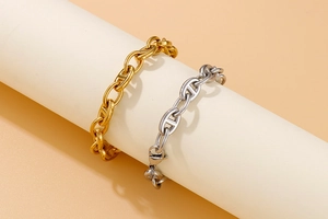 Detail view of gold and silver stainless steel anchor link bracelets on a white display