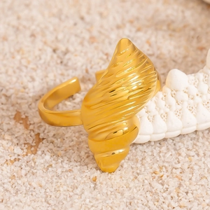 Macro view of gold seashell ring on white sand and coral for beach aesthetics