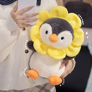Plush penguin doll with yellow sunflower headband held by a person in a cozy setting