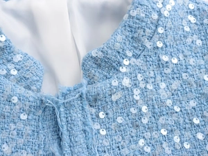 Close-up detail of light blue sequined tweed jacket collar and white inner lining