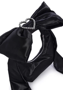 Dettaglio della borsa in raso nero con grande fiocco 3D e fibbia scintillante con cuore di diamanti