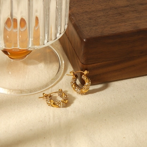 18K gold plated twisted hoop earrings with sparkling stones on linen background