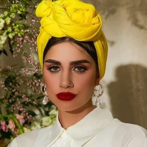 Bright yellow solid color headscarf paired with large pearl drop earrings on a model