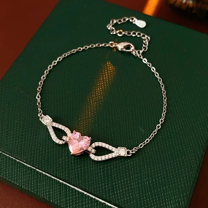 Close-up of pink heart zircon bracelet with silver metal on green leather jewelry box