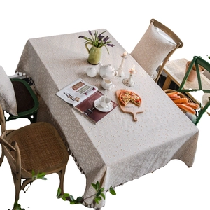 Linen cotton tablecloth with daisy print and tassel fringe on a rustic dining table