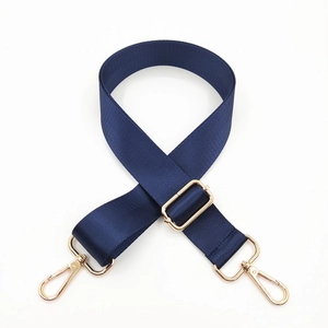 Detail of navy blue nylon bag strap with polished gold-tone metal hooks and adjustable buckle