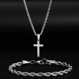 Elegant silver cross pendant necklace and twisted chain bracelet set on black background