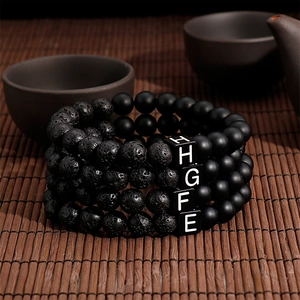Detailed texture of black lava stone bracelets with letter beads on bamboo mat surface