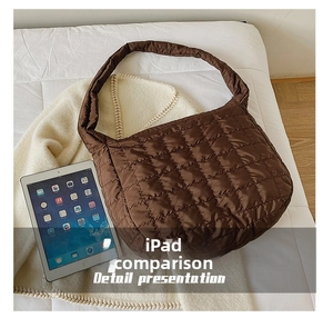 Detail view of large quilted brown shoulder bag with high-gloss nylon finish next to iPad