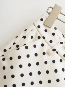 Detail view of white polka dot shorts with black patterns and woven fabric texture