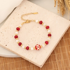 Handmade beaded bracelet with red natural stones and evil eye charm on stone background