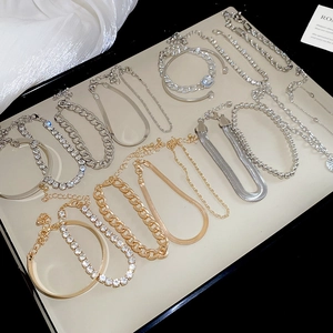 Détail d'un ensemble de bracelets or et argent sur plateau beige avec tissu en soie