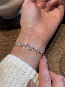 Detail of silver bracelet with bowknot pendant and shimmering moonstones on a model's wrist