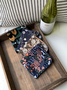 Flat lay of four embroidered linen pouches with floral patterns in a wooden tray