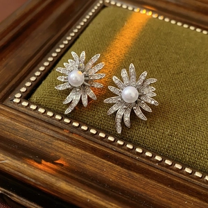 Macro detail of sunflower stud earrings with center pearl and pave cubic zirconia