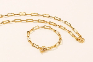 Macro detail of golden paperclip chain necklace and bracelet set with T-bar toggle clasp