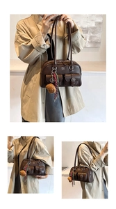 Detalle del bolso tote de cuero marrón oscuro con bolsillos de hebilla y amuleto de oso