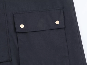 Close-up of contrast-colored flap pocket with two gold buttons on a hooded windbreaker