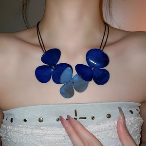 Macro shot of large blue resin flower pendants with gold accents on a cord necklace
