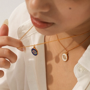Detailed view of evil eye necklaces in gold with blue and white enamel pendants
