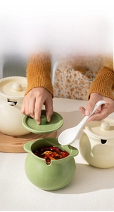 Ceramic seasoning jar detail showing the lid with spoon slot and white ceramic spoon