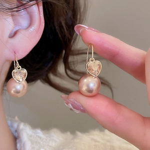 Close-up of champagne pink heart crystal and pearl drop earrings for an elegant style