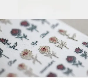 Vue macro d'autocollants 5D pour ongles avec motifs de roses rouges et texte en relief