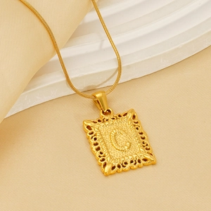 Golden square letter C necklace with fine snake chain on minimalist silk display