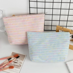 Detail of woven tweed makeup bags in pink and blue with textured knit pattern and zippers
