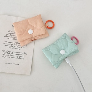 Dettaglio ravvicinato di due custodie AirPods trapuntate nei colori pesca e menta.