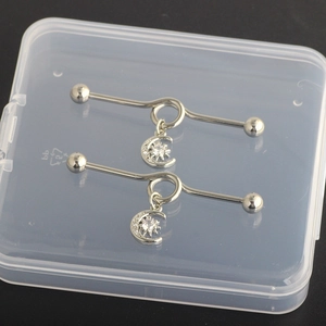 Detail of silver nipple bars with celestial sun and moon pendants set with zircons
