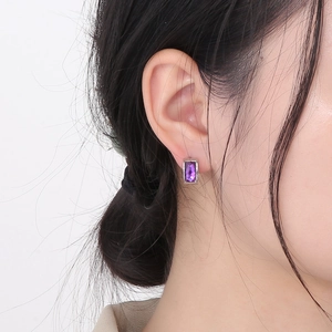 Close-up of a model wearing a minimalist silver stud earring with a purple rectangular gem