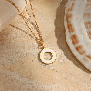 Detail view of a gold-plated necklace featuring a white enamel star charm on silk fabric