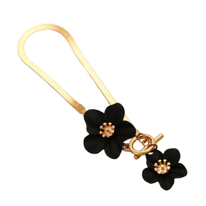 Detail of gold snake chain with black floral charms and a secure toggle clasp closure