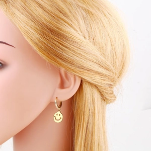 Close-up detail of a model wearing the gold-plated smiling face earrings with tiny crystals