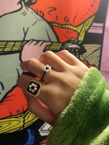 Detailed view of vintage gold plated enamel rings with pearl flowers on a female hand