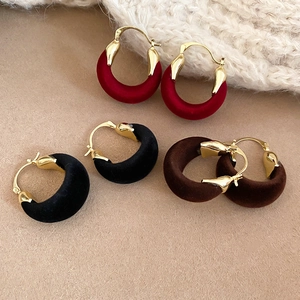 Detailed view of vintage velvet round hoop earrings in red, black, and brown colors