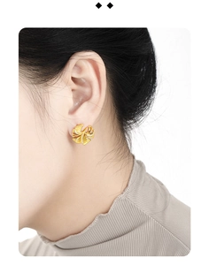 Close-up of golden ginkgo leaf stud earring with delicate crystal accents on model ear