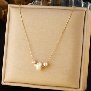Macro shot of gold chain necklace with contrasting large white and small pink pearls