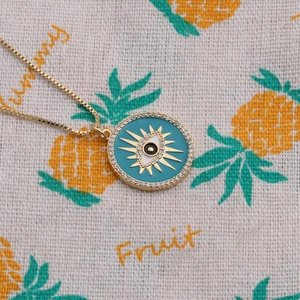 Macro detail of gold evil eye pendant with turquoise enamel and sparkling cubic zirconia