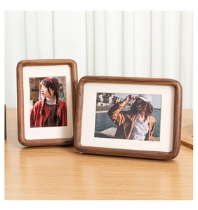 Detail of walnut wood photo frames with rounded corners and white mats in a cozy setting