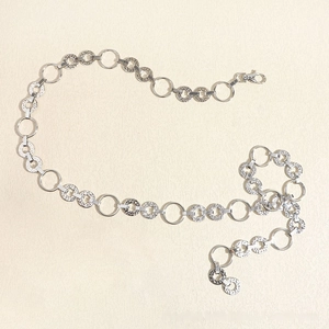 Detail of silver link chain belt featuring polished and hammered metal rings with lobster clasp